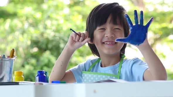 Cute Asian Child Enjoying Arts And Crafts Painting With His Hand