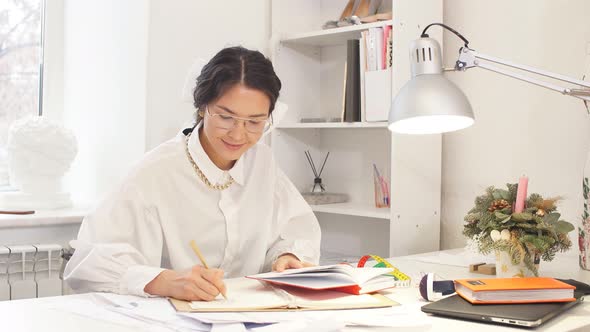 Serious Attractive Tailor Designer Writing in Notebook