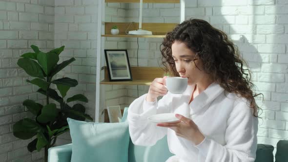 Curly Haired Girl in Bathrobe Looking at Window and Enjoy a Cup of Tea
