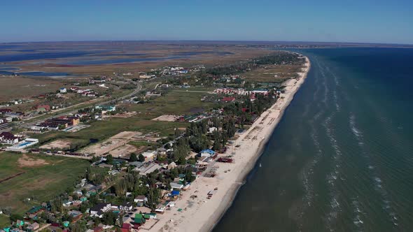 Beautiful flight in summer over the beach. People are resting near the sea. Houses for tourists.