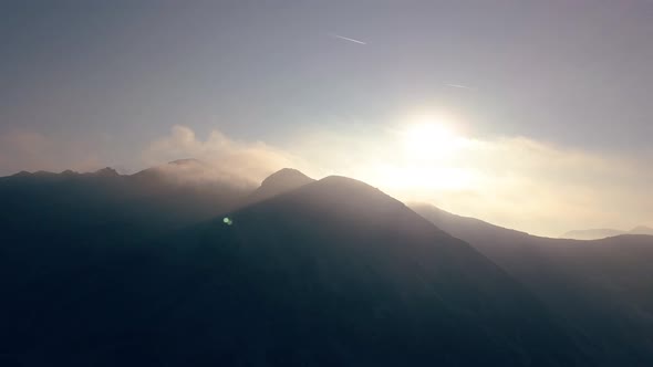 Aerial view of multiple summits in Romania backlit by the sun.