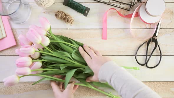 Step by step. Florist wrapping pink tulips in bouquet.