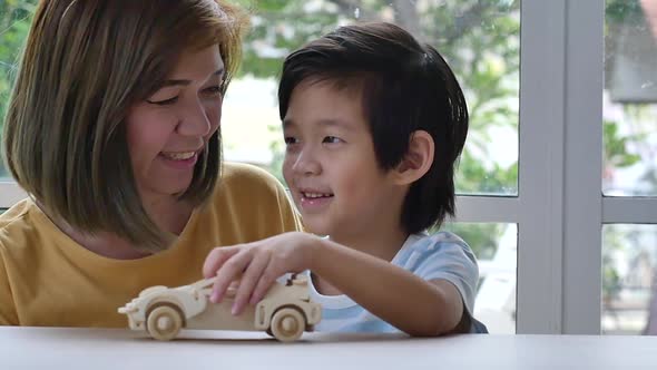 Asian Mother And Son Playing Wood Toy Car Together