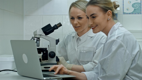 Two young positive scientists working in laboratory using