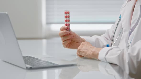 Woman doctor shows blister with small pink pills