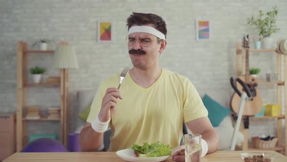 Unhappy Overweight Man with a Mustache with a Bowl of Salad on the Table