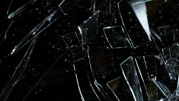 Hammer breaking Pane of Glass against Black Background, Slow Motion