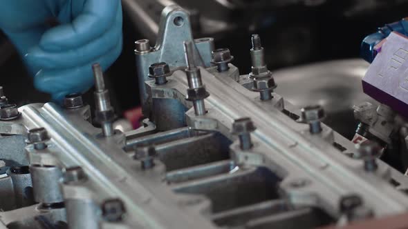 A mechanic hand tightening engine bolts with blue latex disposable gloves.