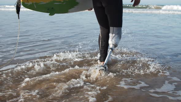 Back View of Surfer with Disability in Wetsuit Entering Ocean