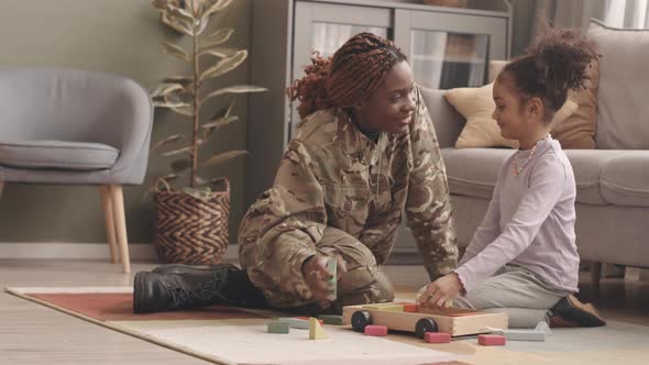 Military Woman and Her Little Daughter Playing with Toys at Home alt