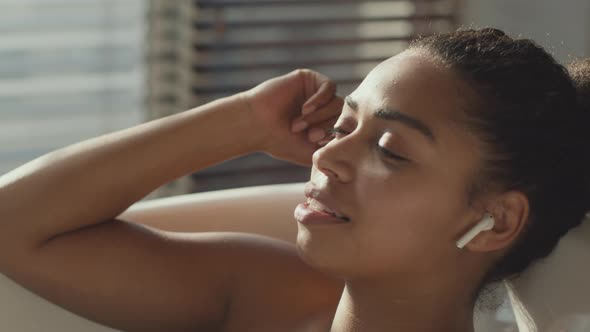 Young Carefree African American Woman Listening to Music and Singing Relaxing in Bathroom with