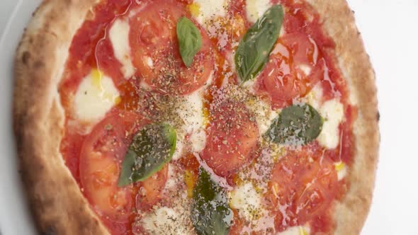 Vertical video: Pizza sprinkled with Italian spices