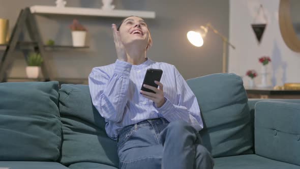 Hispanic Woman having Success on Smartphone at home