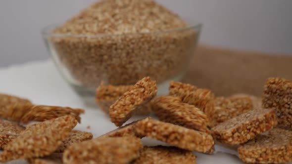 View of bowl filled with sesame seeds and sticks, Sticks of sesame seeds falling on plate