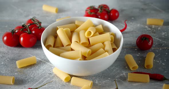 Dry Cannelloni Pasta in a Bowl with Tomatoes Slowly Rotates. 