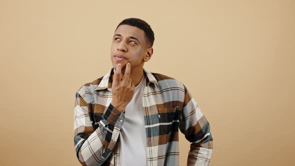 Studio Portrait of Young Stylish Pensive African American Guy Thinking Compering Ideas and Solutions