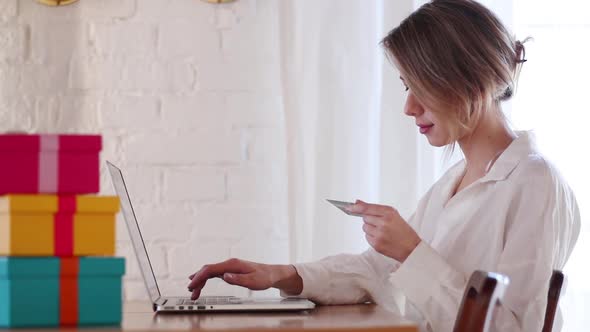 girl with holiday gift boxes and laptop computer and credit card