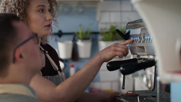 Caucasian man with down syndrome helping waitress in making coffee. Shot with RED helium camera in 8