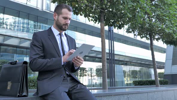 Businessman Using Tablet Computer While Sitting Outside Office