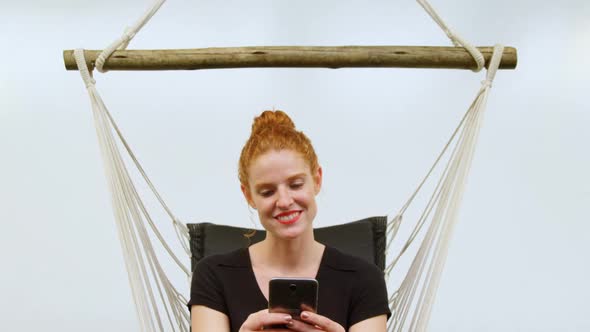 Businesswoman using mobile phone while relaxing on a hammock