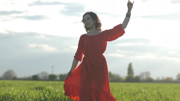 Beautiful Spanish Brunette Woman in Red Dress Dancing at Sunset in Wheat Field