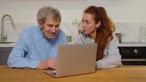 Smiling Young Attractive Woman Discussing Internet Shopping with Older Mature Father Looking at