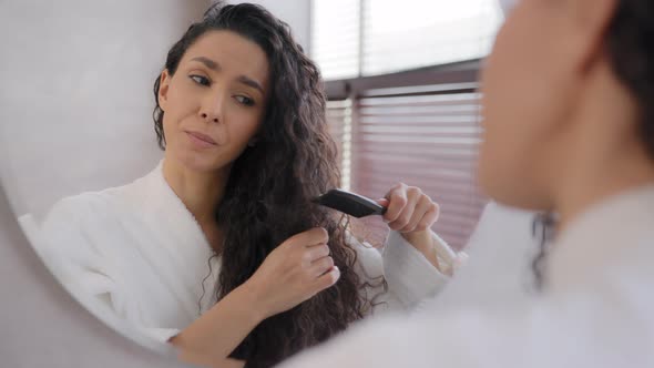 Closeup Young Woman Looking in Mirror Combing Hair in Bathroom Annoyed Sad Girl Dissatisfied Damaged