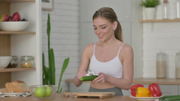 Healthy Woman Peeling Cucumber While Standing in Kitchen