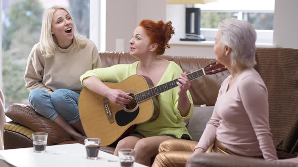 Talented Adult Woman Playing Guitar Singing with Friends Resting on Weekend