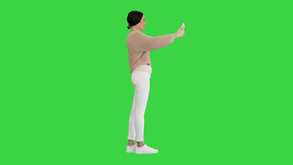 Smiling Young Woman Having Video Call on Her Phone Waving Hand on a Green Screen Chroma Key