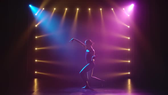 Professional Ballerina in Black Bodysuit Gracefully Dancing Ballet in Dynamic Spotlights and Smoke