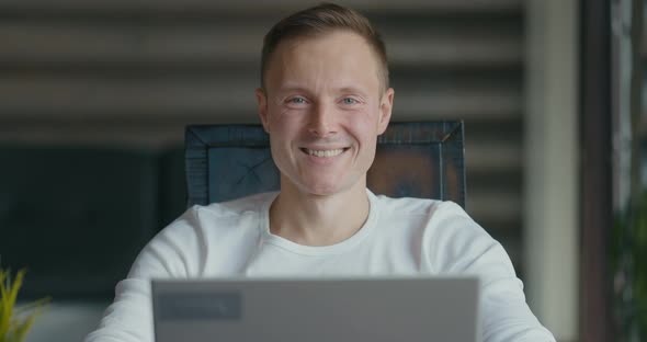 Portrait of Smiling Young Man Sitting at Laptop in the Room