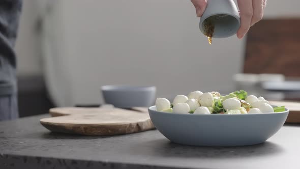 Slow Motion Man Pour Dressing Over Salad with Kale Mozzarella Avocado and Cherry Tomatoes