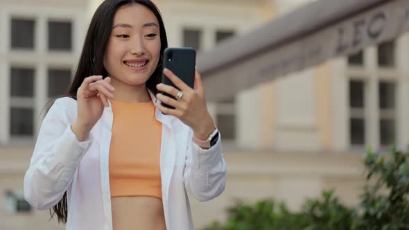 Happy Asian Woman Speaking on Video Call in Street
