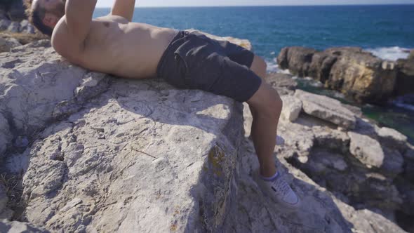 Athlete man lifting weights on the beach.