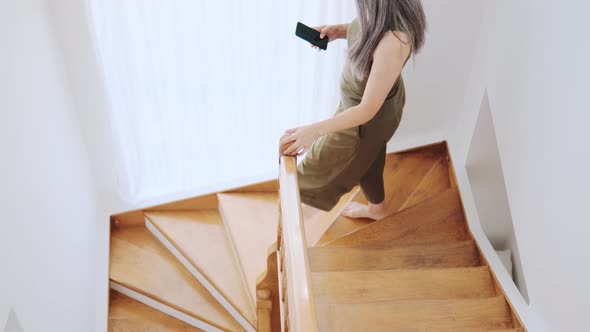 Asian woman walking on the stairs and looking at the phone