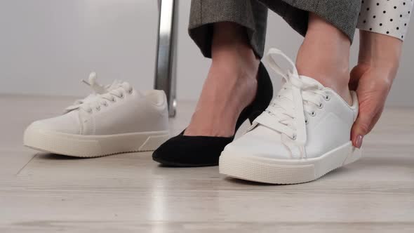 Business Woman Takes Off White Leather Sneakers and Puts on Black High Heel Shoes
