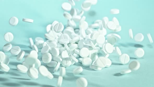 Super Slow Motion Shot of Falling White Pills on Light Green Background at 1000Fps