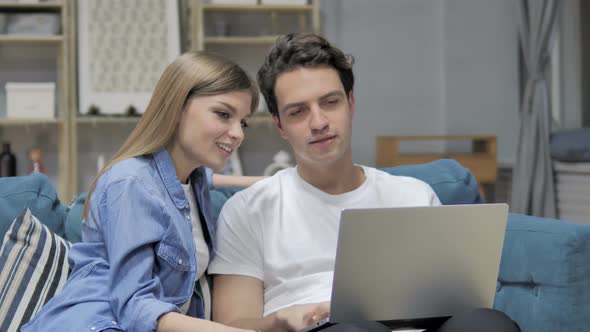 Young Couple Discussing Online on Laptop at Home