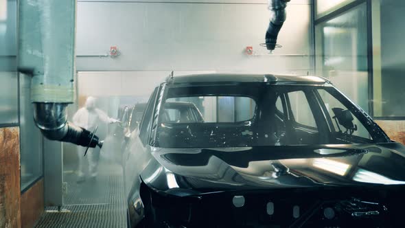 Car Body Being Painted Black By Robotic Arms