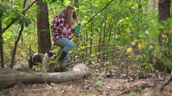 Wide Shot Green Summer Forest in Sunshine with Young Woman and Dog Entering in Slow Motion