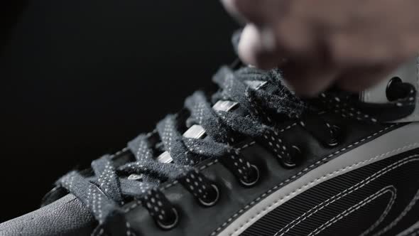 A Player in Hockey Ties Laces on Skates a Black Background