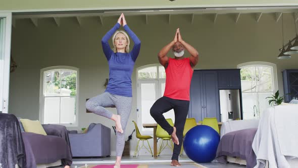 Mixed race senior couple practicing yoga together at home