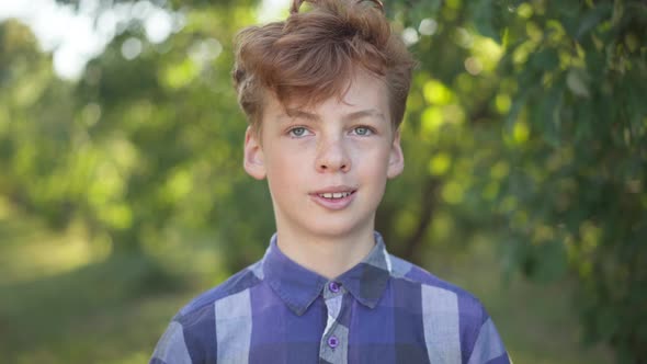 Closeup Portrait of Confident Caucasian Teenage Boy with Red Curly Hair Smiling Looking at Camera