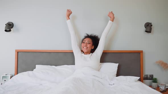 Positive African pregnant woman stretching after sleep