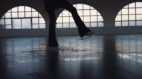 Young Woman is Skating on Dark Ice Arena