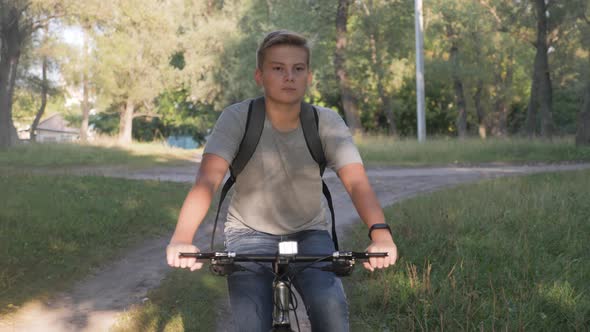 Teenage Boy Rides Bike in City Park at Sunny Day. Healthy Lifestyle Concept.