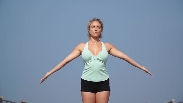 A young attractive woman doing yoga on the pier.