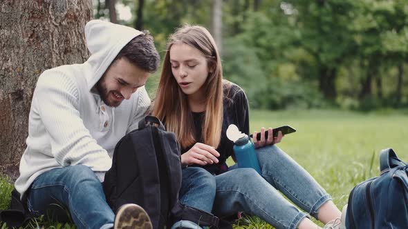 People Sitting in a Summer Forest with Bootle of Water