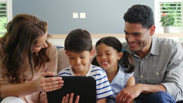 Happy family using digital tablet in living room